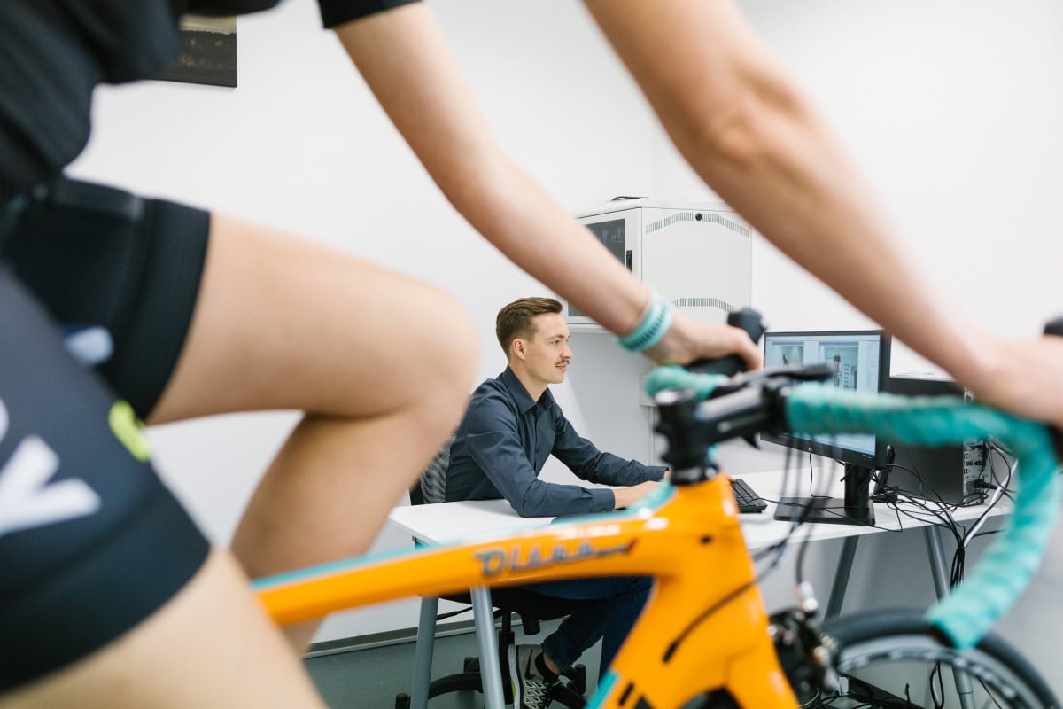 BikeFitter beobachtet einen Radsportler auf dem Rennrad im HYCYS-Labor